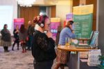 Attendees enjoying interactive research displays at Stories of Impact event, December 2024